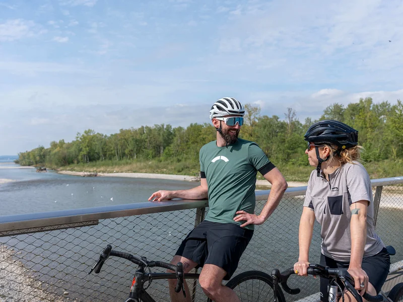 Gravelbike Holidays © Chris Gollhofer - Vorarlberg Tourismus Zwei Radfahrer stehen auf einer Brücke und unterhalten sich