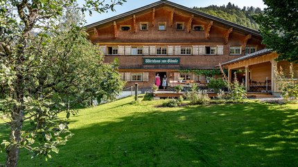Gämsle Hotel, Wirtshaus & mehr © Raffael F. Lehner Traditionelles Gasthaus in einer grünen Landschaft mit zwei Personen an der Tür
