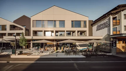 Dips&Drops - HOTEL · SPORTS · SPA · RESTAURANTS © Matthias Warter Außenansicht von Dips & Drops Bistro mit Terrasse und Gästen bei Sonnenlicht