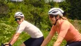 Gravelbike Holidays © David Lemanski Zwei Radfahrer fahren in sportlicher Kleidung auf einer Straße mit Wald im Hintergrund