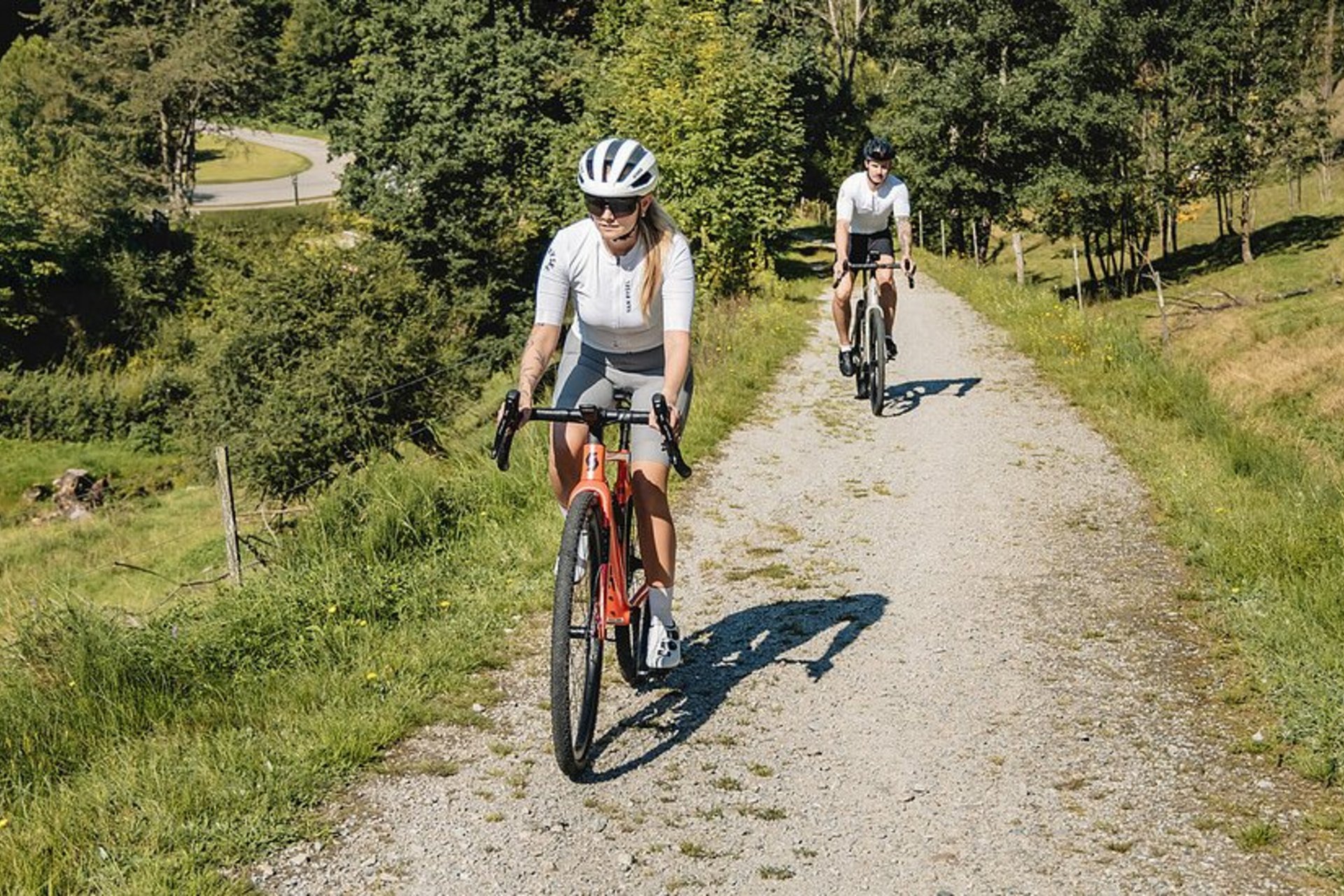 Gravelbike Holidays © Stefan J. Wolf Photography Zwei Radfahrer auf einem Waldweg bei sonnigem Wetter