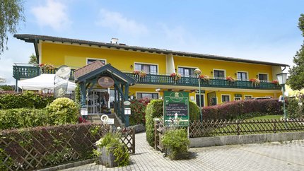 Landgasthof Krumbacherhof © Wiener Alpen Croy Gelbes Hotel mit grünem Eingang und Blumen an der Terrasse