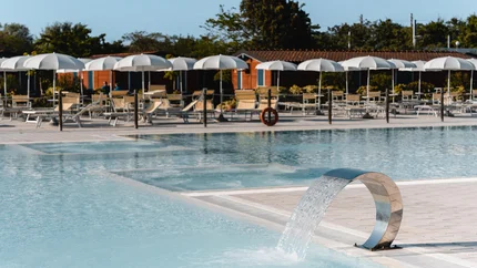 Natural Village Resort © Luigi Ventimiglia Moderner Pool mit Wasserfontäne und Liegestühlen unter weißen Sonnenschirmen