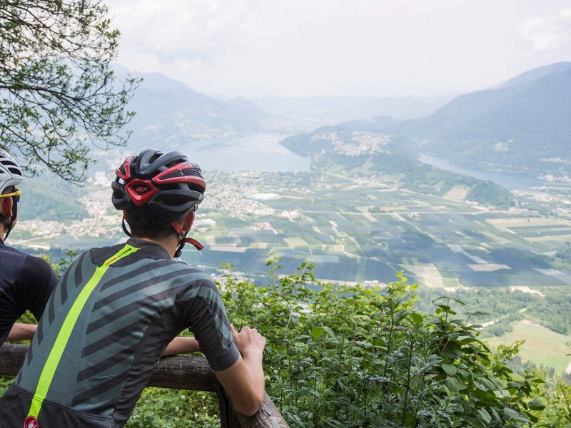 Gravelbike Holidays © Heiko Mandl Zwei Radfahrer blicken von einem Berg auf ein Tal mit Fluss und Feldern