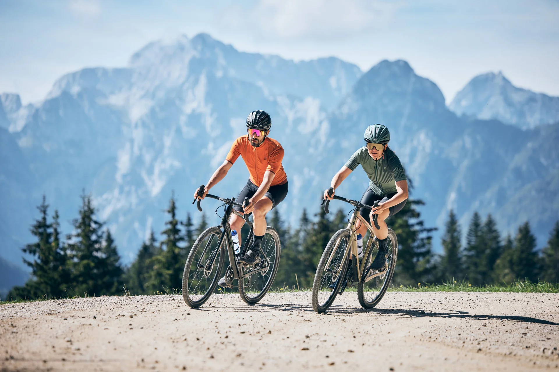 Gravelbike Holidays © Tobias Köhler Zwei Radfahrer fahren auf Bergweg mit Bergpanorama im Hintergrund