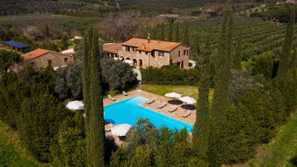 Tenuta Il Cicalino © Tenuta il Cicalino Steinhaus mit Pool umgeben von Bäumen in einer grünen Hügellandschaft