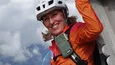 Gravelbike Holidays © Hotel Innerhofer Frau mit Helm und orange Jacke beim Klettern an Holzstruktur in den Bergen