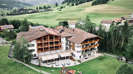 Hotel Bogner Hof © Hotel Bogner Hof GmbH & Co KG Blick auf ein Hotel im Bergtal mit grünen Wiesen und Bergen im Hintergrund