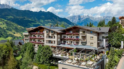 Aktivhotel Alpendorf © Atelier Oczlon Hotel Alpendorf mit Terrasse in bergiger Landschaft bei Sonnenschein